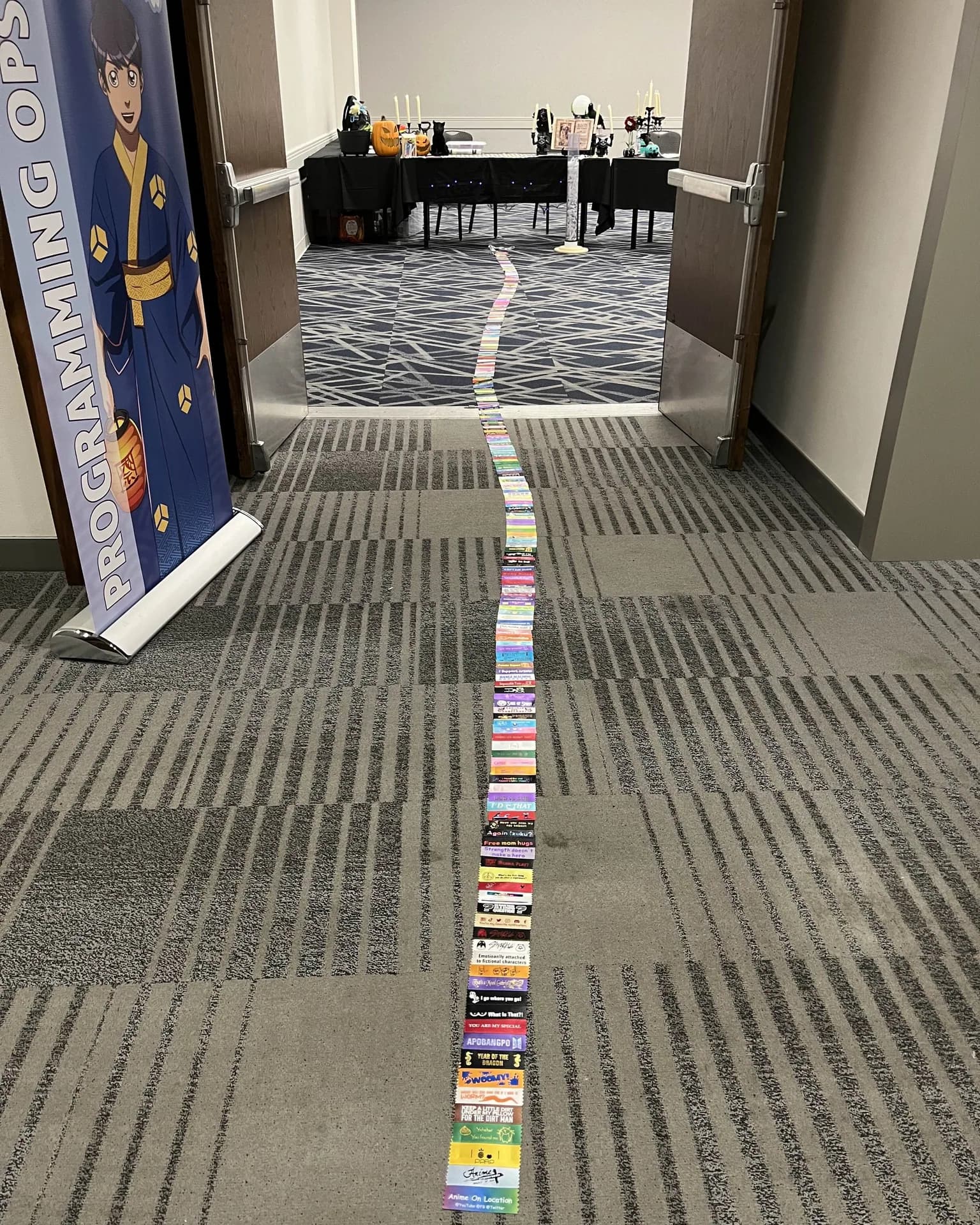 A long chain of colorful badge ribbons stretches down a Matsuricon hallway and into a programming room.