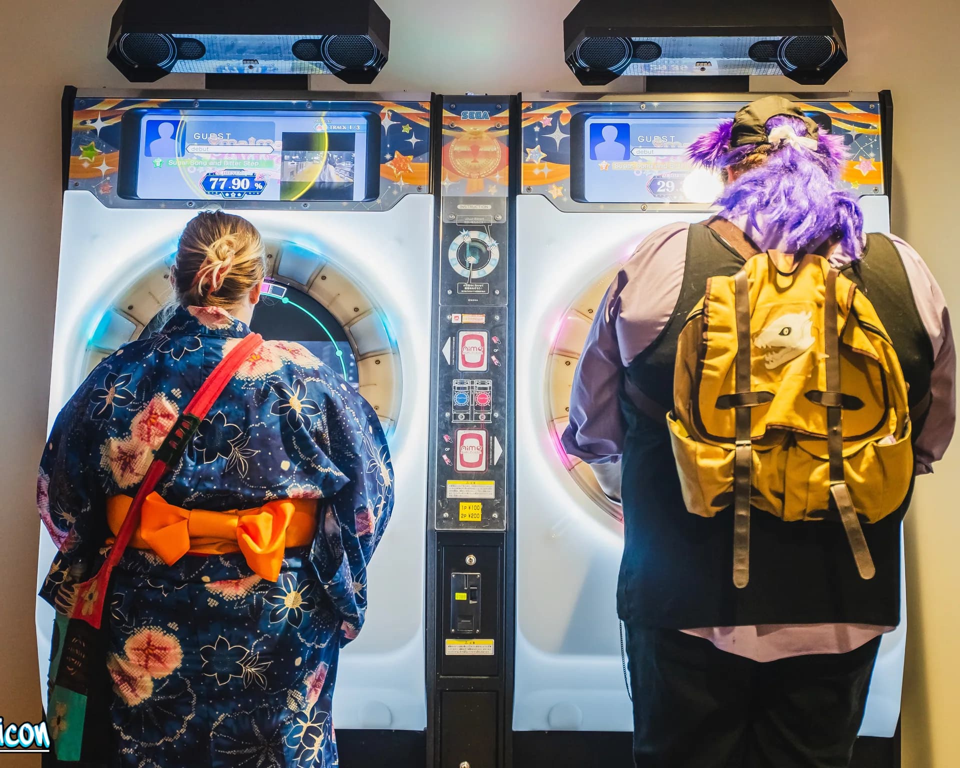 Two Matsuricon attendees play side by side on matching circular rhythm arcade machines.