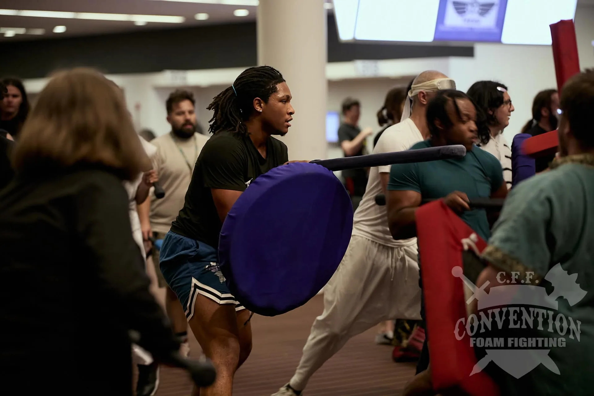 Convention Foam Fighting participants move through a group battle carrying colorful foam swords and shields.