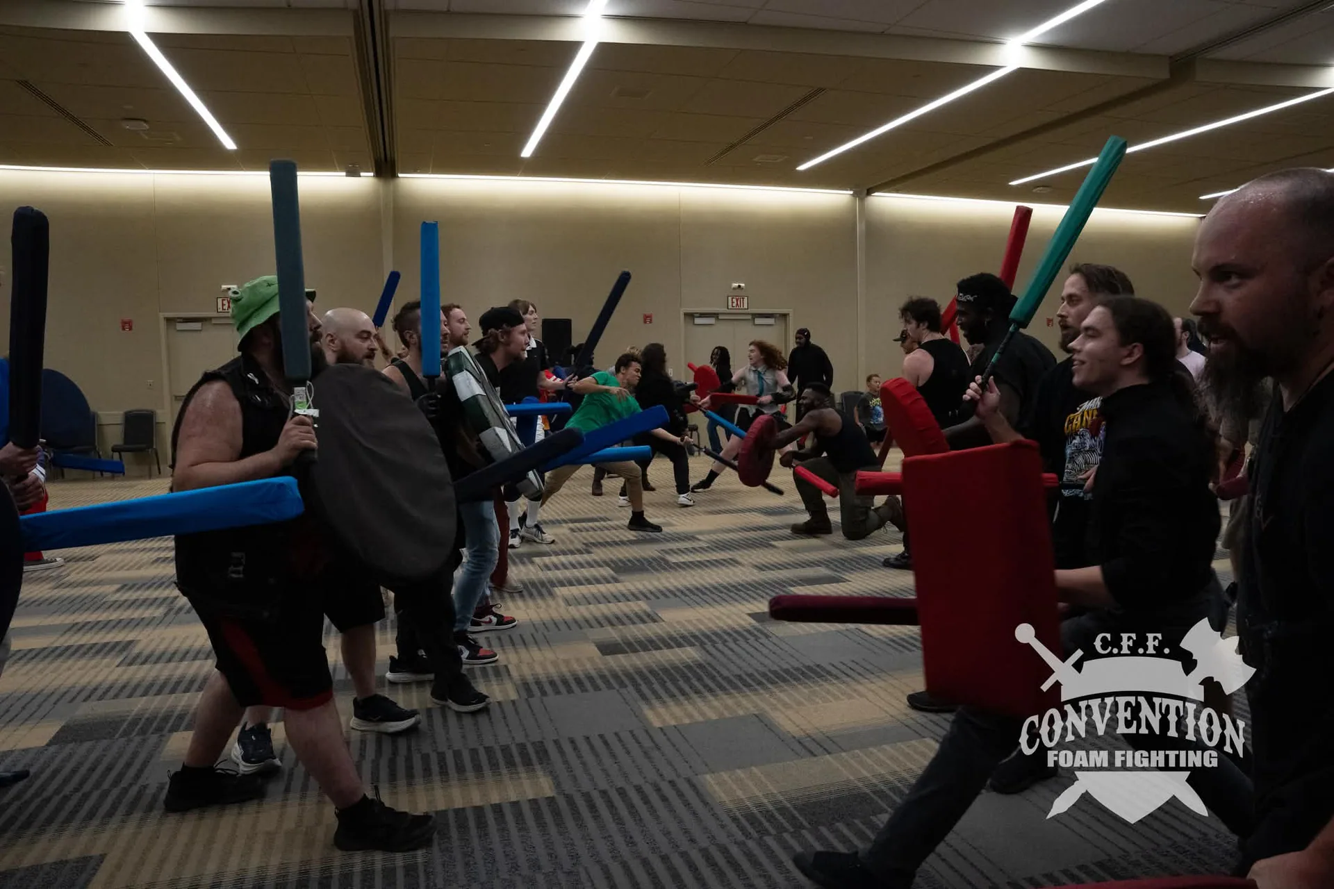 Convention Foam Fighting participants face off in two lines with colorful foam swords and shields.